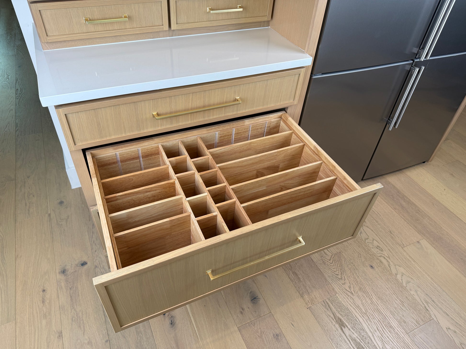 Open kitchen drawer with wooden organizer in a modern kitchen setting
