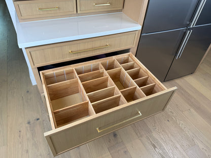 Open kitchen drawer with wooden compartments in a modern kitchen setting.