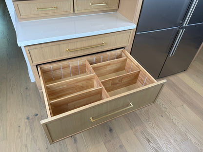 Open kitchen drawer with wooden interior in a modern kitchen setting