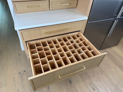 Open kitchen drawer with wooden compartments in a modern kitchen setting.