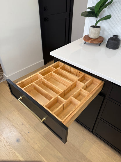 Open wooden drawer with compartments in a kitchen setting