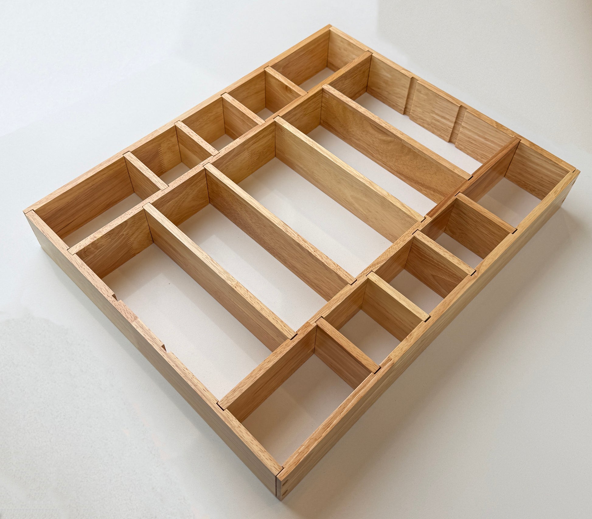 Wooden drawer organizer with multiple compartments on a white background